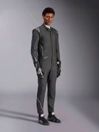 Alpinestars Hypertech V3 Anzug, Auto-Rennanzug, Schwarz und Dark Shadow, getragen von einem männlichen Model mit passenden schwarzen Handschuhen und Rennschuhen, sportlich schlanke Passform, mit Alpinestars-Logos und hellgrauen Akzenten, professionelle Motorsport-Schutzausrüstung