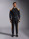 Alpinestars GP Pro Comp V2 FIA Rennanzug, Autorennanzug in Schwarz Asphalt und Orange Fluo, männliches Model in vollständiger Schutzausrüstung mit passenden Rennhandschuhen und Schuhen, weiße Alpinestars-Logos und leuchtend orangefarbene Seitenpaneele, professionelle Motorsport-Bekleidung