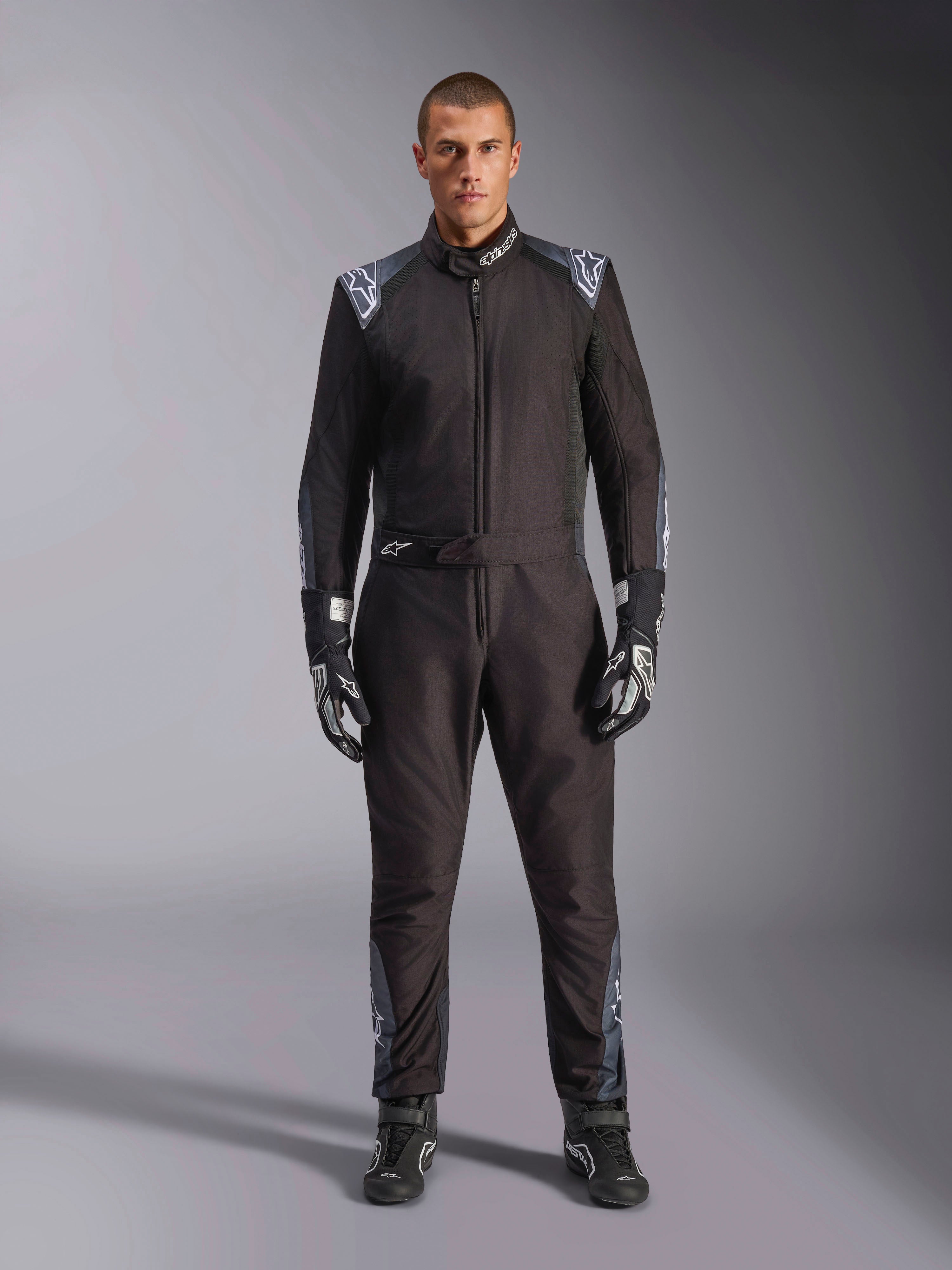Alpinestars KMX-5 V3 Anzug, Karting-Anzug, Schwarz Dark Shadow, Ganzkörperansicht eines Models im Anzug mit passenden Handschuhen und Stiefeln, mit dunkelgrauen Akzenten und weißen Alpinestars-Logos auf Schultern und Gürtel, professionelle Motorsport-Rennausrüstung.