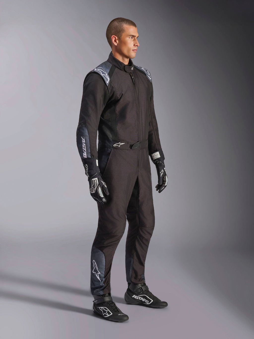 Alpinestars KMX-5 V3 Anzug, Kart-Anzug in Black Dark Shadow, getragen mit passenden schwarzen Rennhandschuhen und Schuhen, mit lasergeschnittenen Perforationen und Tech-Mesh-Einsätzen, elegantes zweilagiges Design mit weißem Branding für den professionellen Motorsport