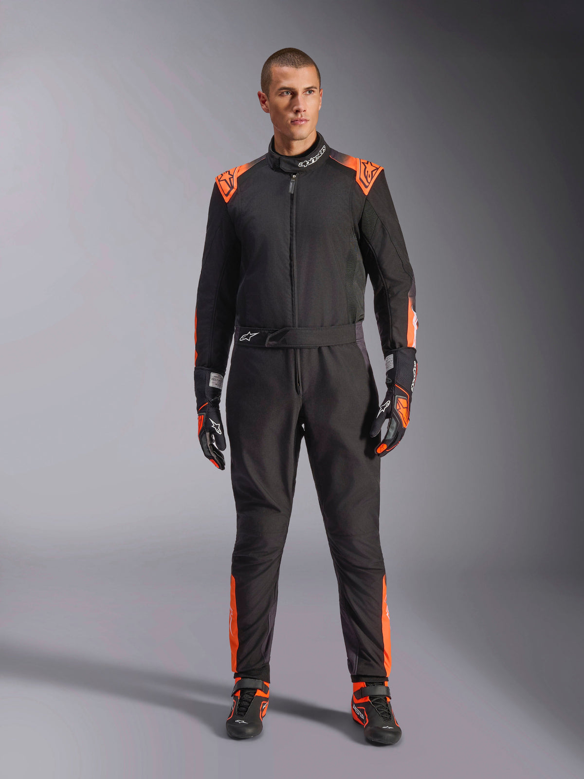 Alpinestars KMX-5 V3 Kombi, einteiliger Herren-Kartanzug für den Rennsport, Schwarz und Orange Fluo, FIA 8877-2022 Grad 1 zertifiziert, am Model präsentiert.