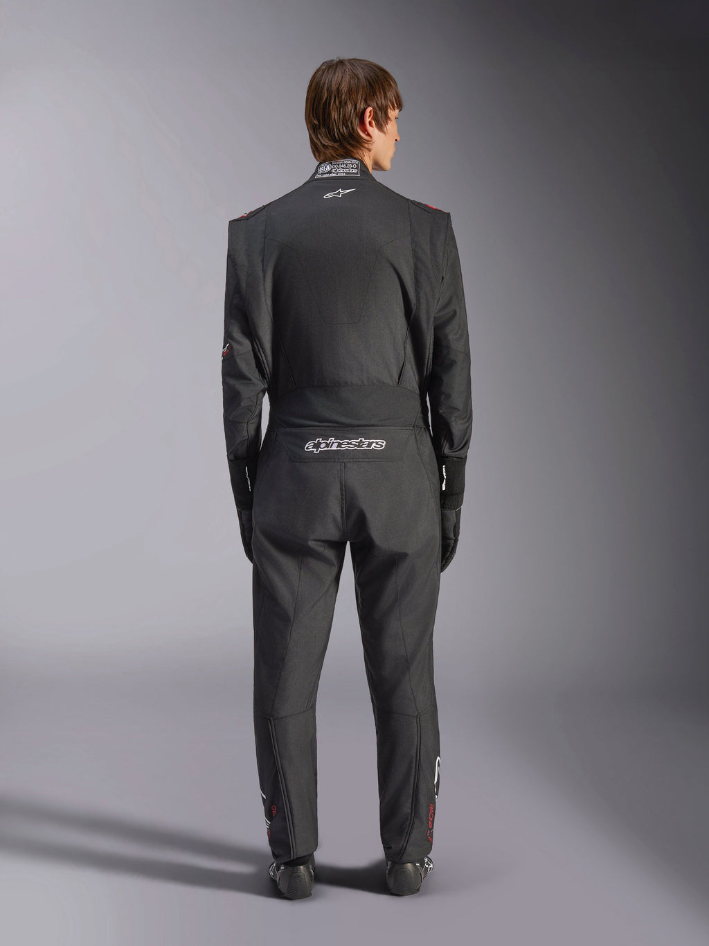 Alpinestars GP Tech V4 Anzug, Auto-Rennanzug, Schwarz und Weiß, Rückansicht mit weißem Alpinestars-Branding und FIA-Zertifizierung am Kragen, schlanke ergonomische Passform für professionellen Fahrerschutz