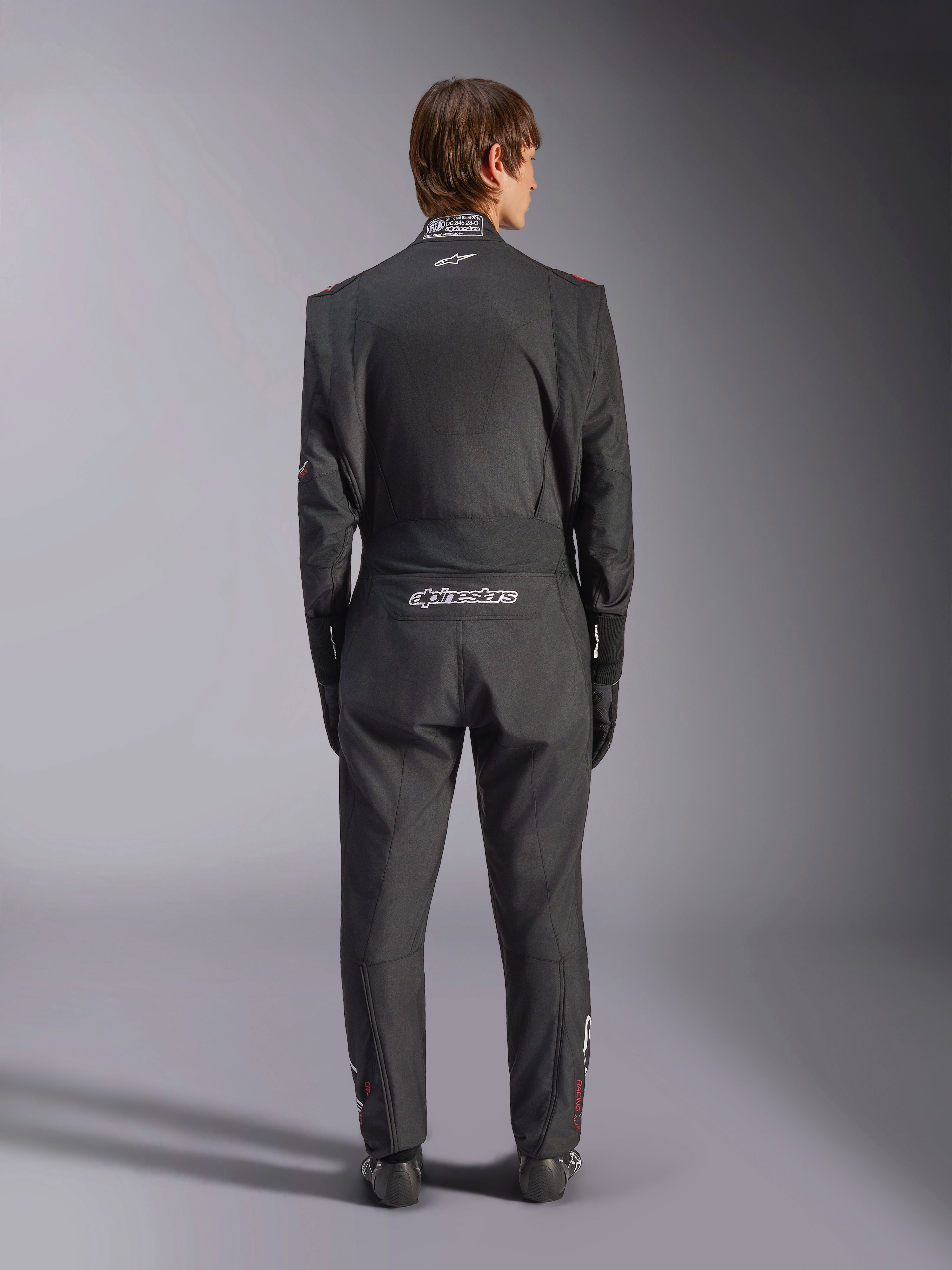 Alpinestars GP Tech V4 Anzug, Auto-Rennanzug, Schwarz und Weiß, Rückansicht mit weißem Alpinestars-Branding und FIA-Zertifizierung am Kragen, schlanke ergonomische Passform für professionellen Fahrerschutz