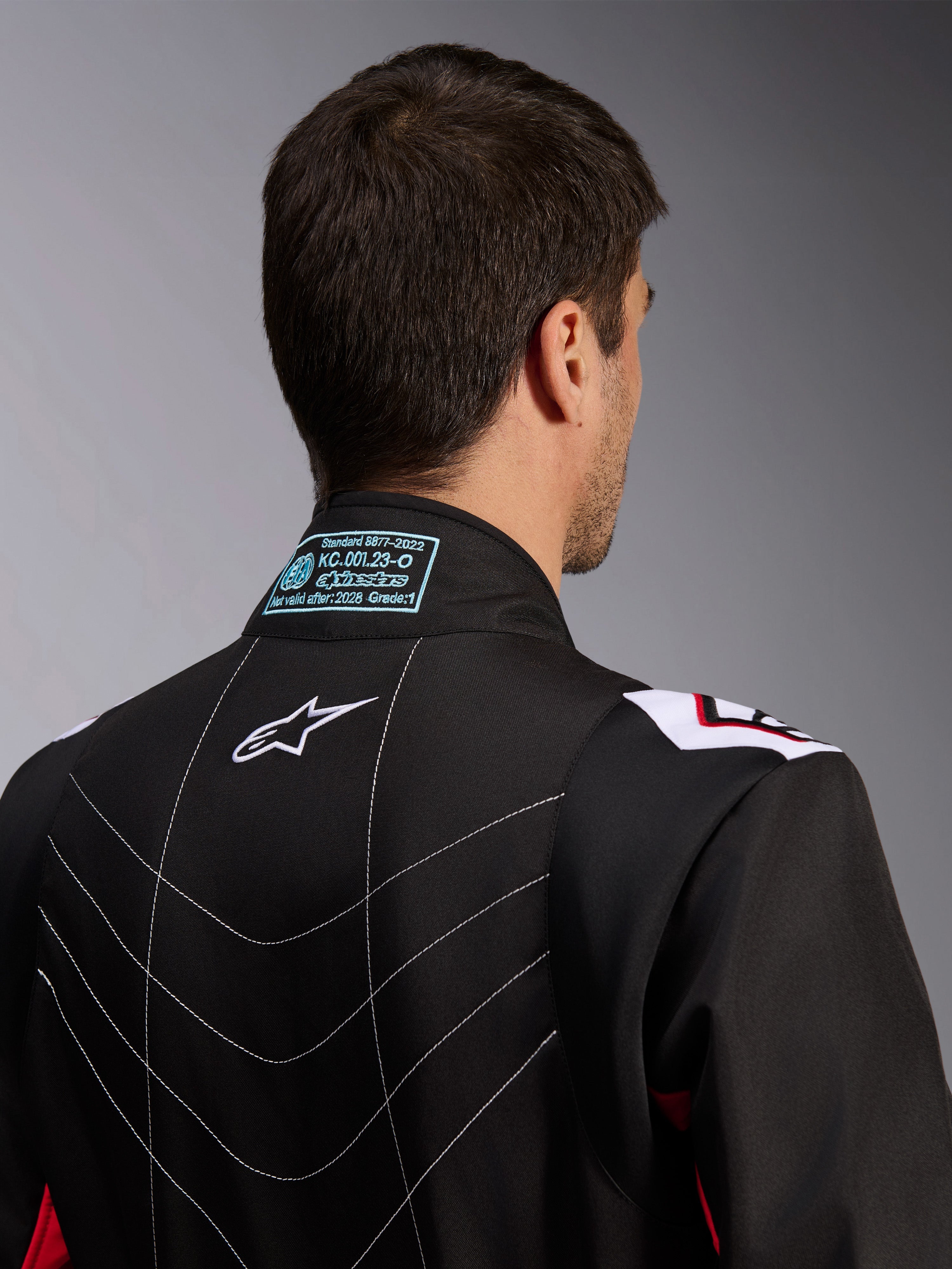 Alpinestars KMX-9 V3 Anzug, Kartanzug, Schwarz Rot Weiß, Rückansicht des Kragens mit FIA 8877-2022 Homologationsetikett, weißem Astars-Logo und dekorativen Nahtdetails