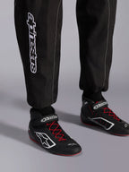Alpinestars KMX-9 V3 Anzug, Kart-Anzug, Schwarz, Rot und Weiß, Detailansicht der Unterschenkel und Karting-Stiefel, weißes Alpinestars-Branding an der Seite, schwarze Schuhe mit roten Schnürsenkeln und weißen Akzenten, professionelle Motorsport-Rennausrüstung.