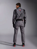 Alpinestars KMX-9 V3 Graphic 5 Anzug, Karting-Anzug, dunkelgraues und schwarzes Camouflage-Muster am Oberkörper, Rückansicht mit Stretcheinsätzen und Alpinestars-Branding, kombiniert mit schwarzen Handschuhen und schwarzen Rennschuhen mit roten Details, professionelle Motorsport-Rennausrüstung