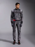 Alpinestars KMX-9 V3 Graphic 5 Anzug, Kartanzug, Dunkelgrau und Schwarz mit Grafiken im Camouflage-Stil, mit schwarzem Brustband mit weißem Logo und rotem Akzent am Taillengürtel, getragen mit passenden Rennhandschuhen und Schuhen, professionelle Motorsportausrüstung