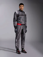 Alpinestars KMX-9 V3 Graphic 5 Anzug, Kart-Anzug, Dunkelgrau und Schwarz mit Camouflage-Grafikmuster, roter Taillengürtel mit weißem Logo, getragen mit Rennhandschuhen und Rennschuhen, professionelle Motorsport-Ausrüstung für den Kartsport
