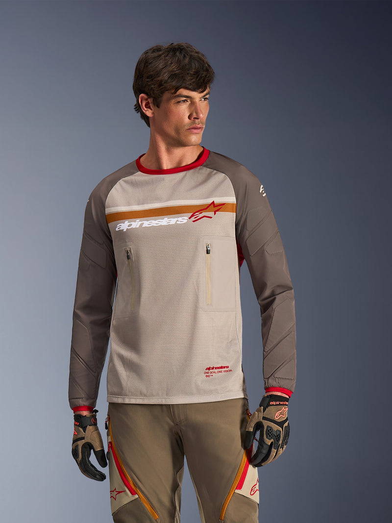 Alpinestars Maxdura Dual Jersey in Aluminum Walnut, adventure motorcycle jersey featuring a breathable mesh torso, walnut brown abrasion-resistant sleeves, and zippered chest pockets, worn by a model with matching off-road gear.