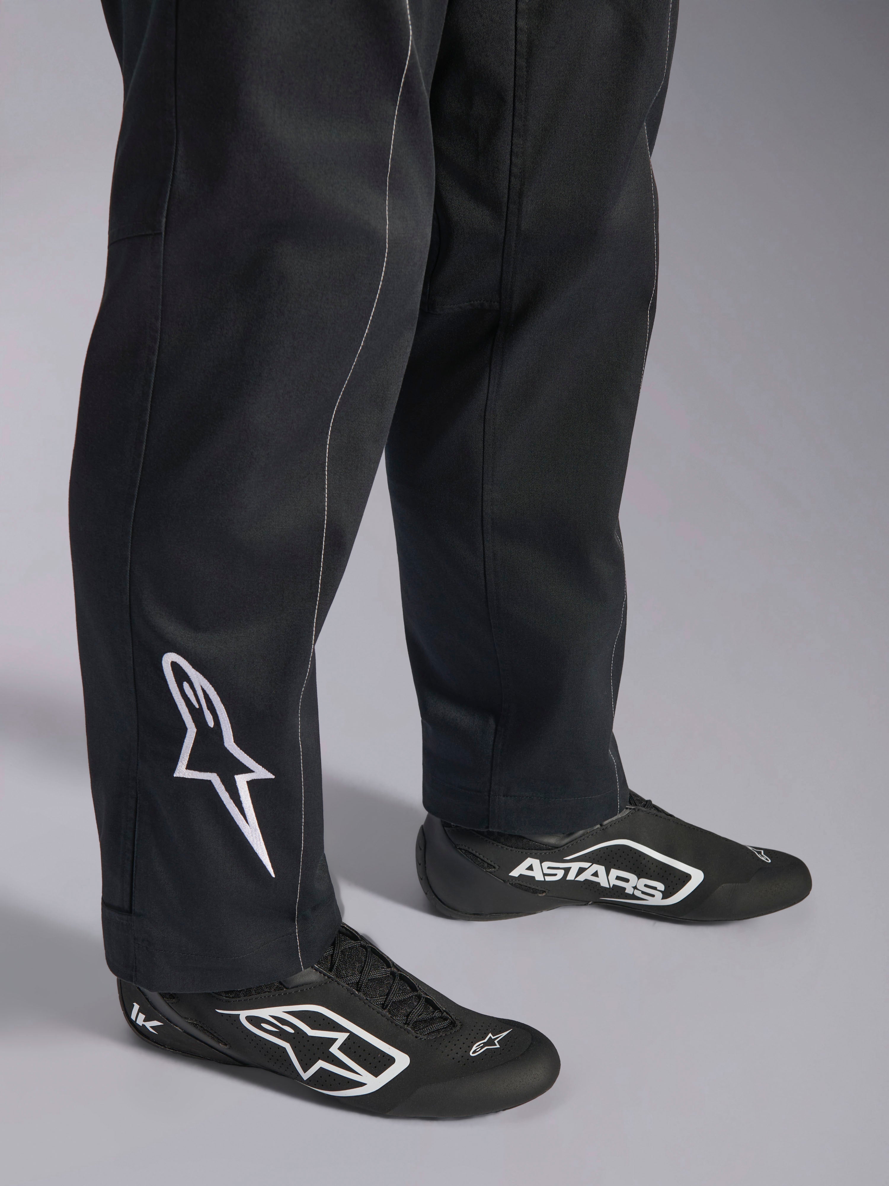 Alpinestars Kart Indoor V2 Suit, Black karting suit, close-up of lower legs and feet featuring a white Alpinestars logo on the calf, worn with matching black and white racing shoes, designed for recreational karting.