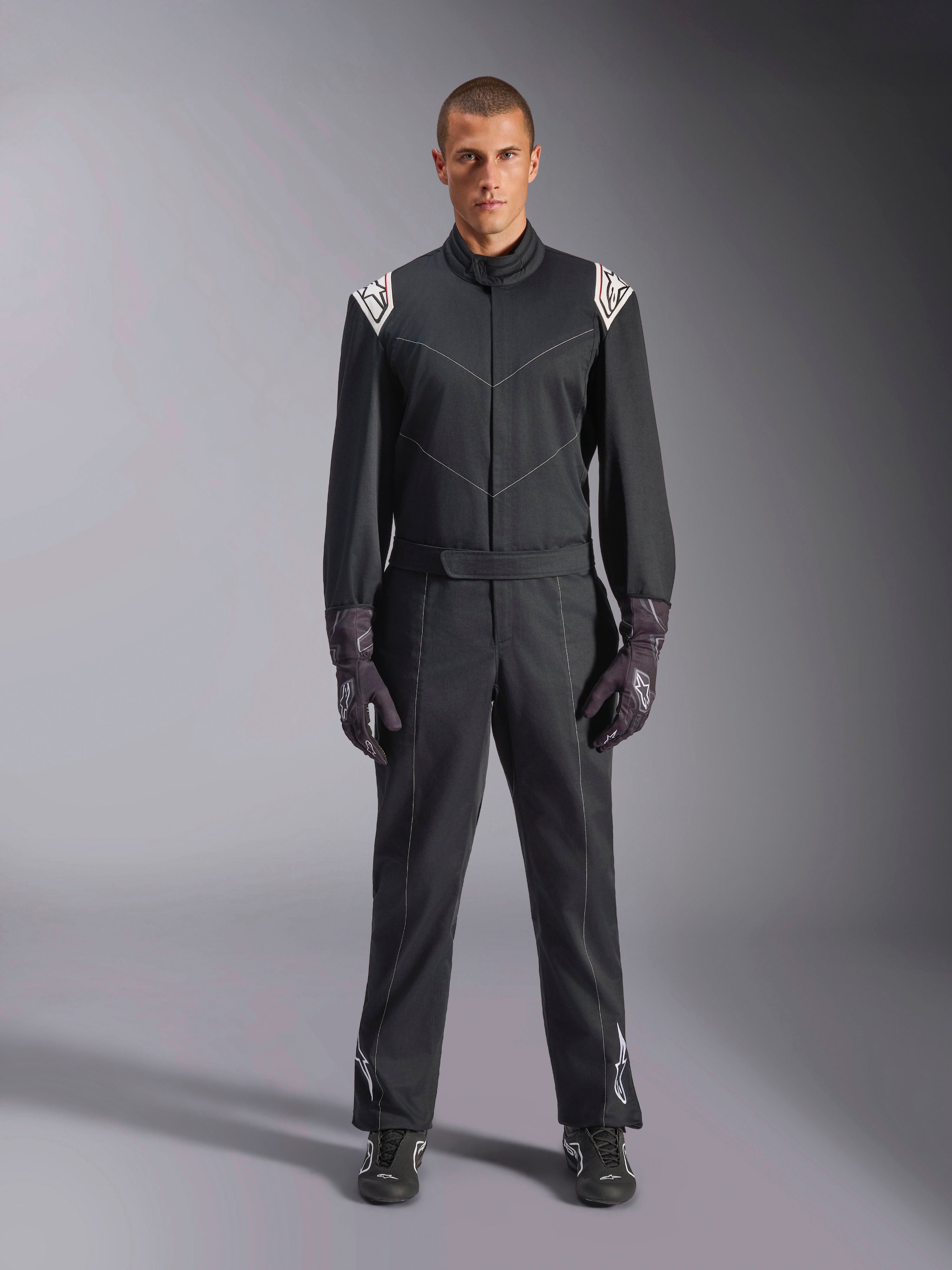 Alpinestars Kart Indoor V2 Suit, One-piece Karting Suit, Black, featuring white Astars logos on the shoulders and lower legs, adjustable waist belt and ergonomic collar, designed for recreational indoor karting