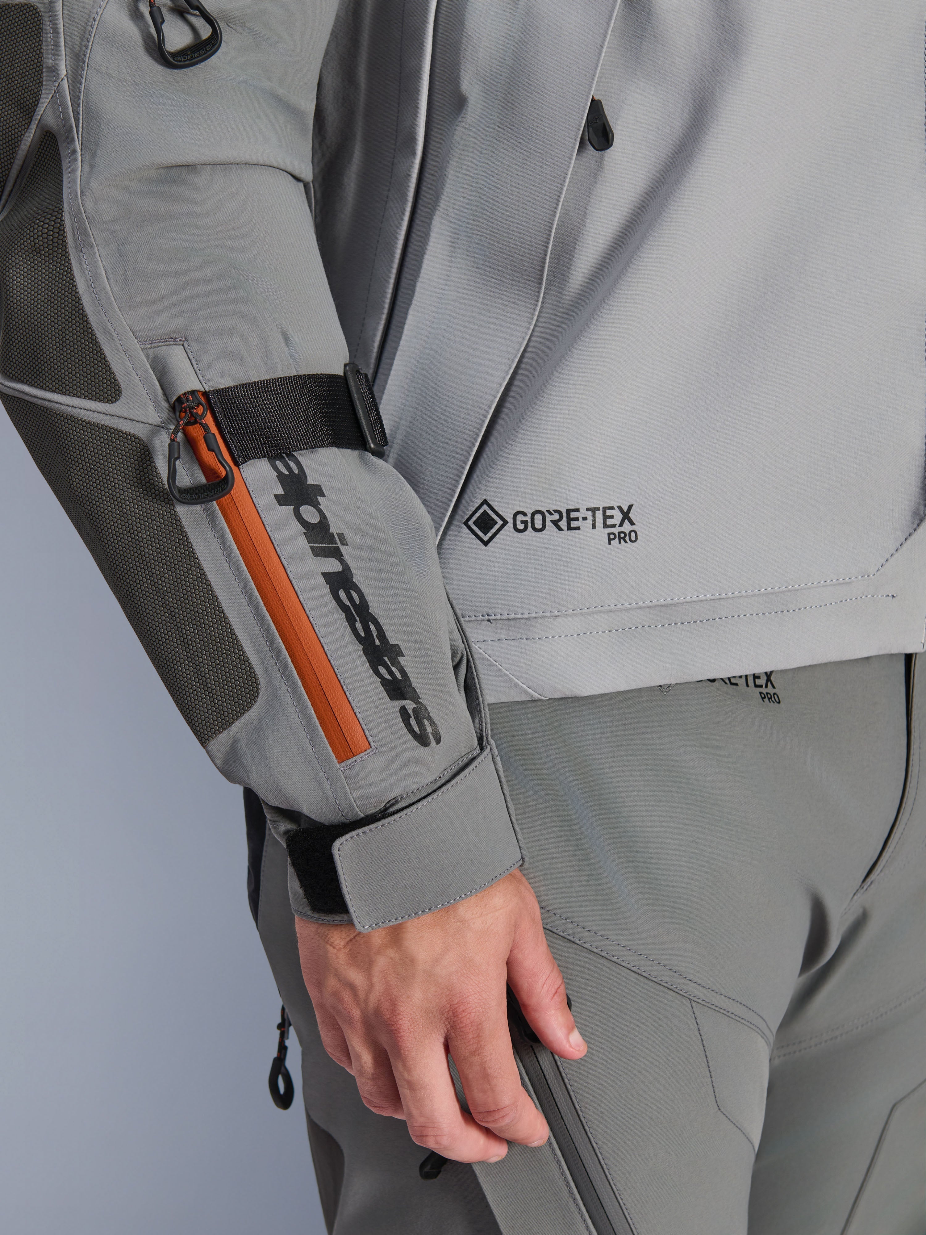 Alpinestars Nazca 3L GORE-TEX PRO Jacket, Dark Gray and Mid Gray adventure jacket, close-up detail of sleeve with black branding and orange zipper accent, GORE-TEX PRO logo on torso, durable textile construction with reinforced elbow patch