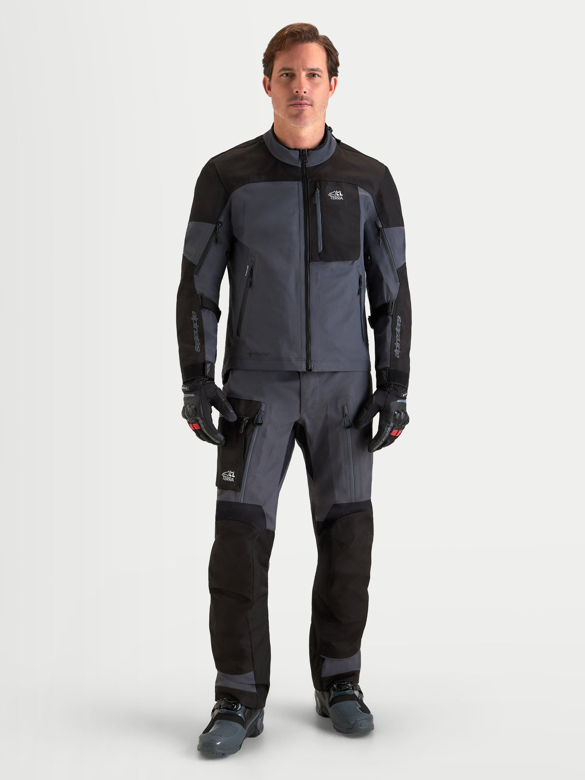 Alpinestars Arenis Gore-Tex Jacke, Herren-Adventure-Motorradjacke in Schwarz und Dunkelgrau, Vorderansicht eines männlichen Models in wasserdichter Textilausrüstung mit CE-Protektoren