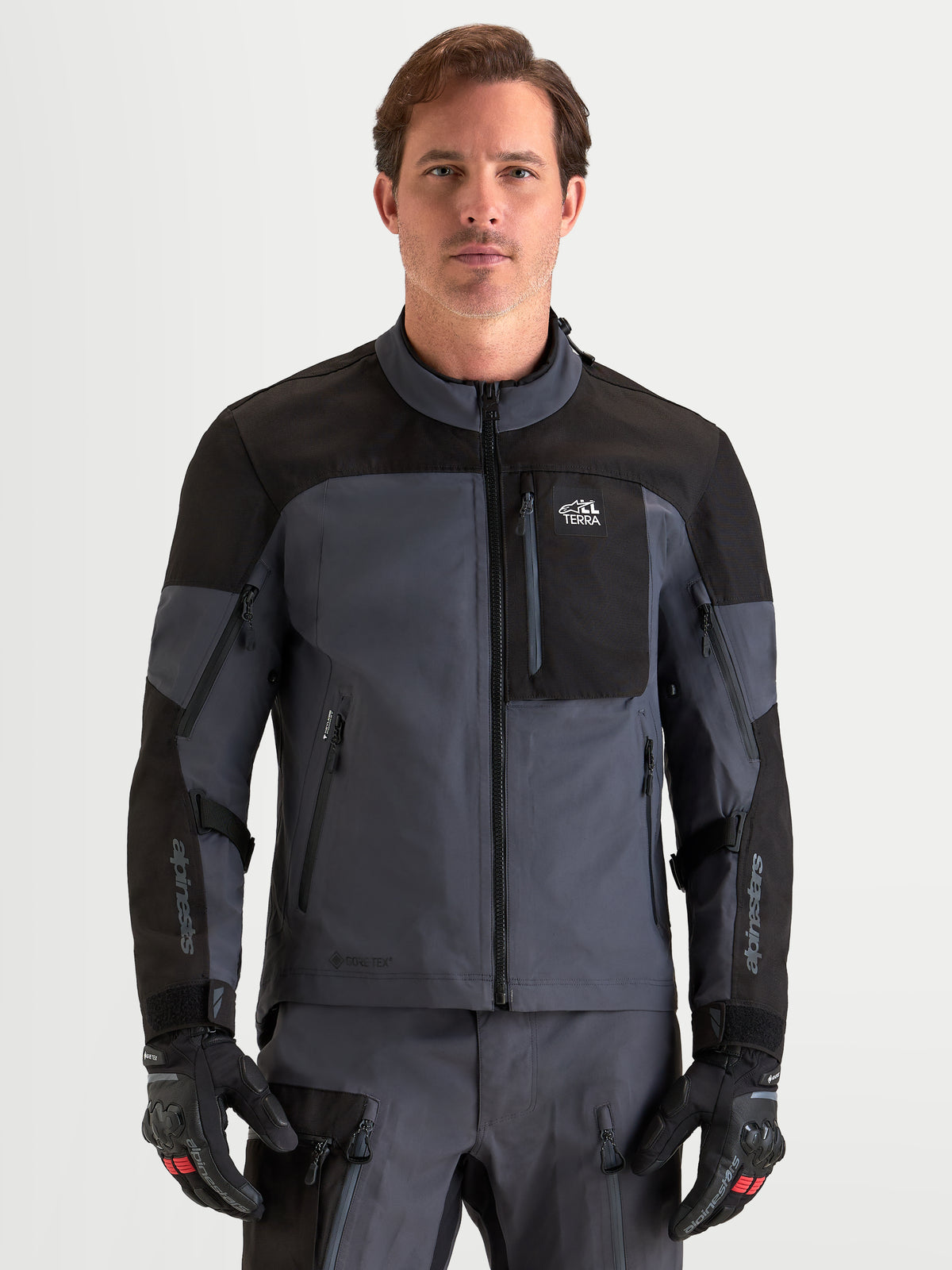 Alpinestars Arenis Gore-Tex Jacket, men's adventure touring motorcycle jacket in black and deep gray, front view on a model wearing matching gear and gloves, AA certified waterproof all-terrain riding apparel.