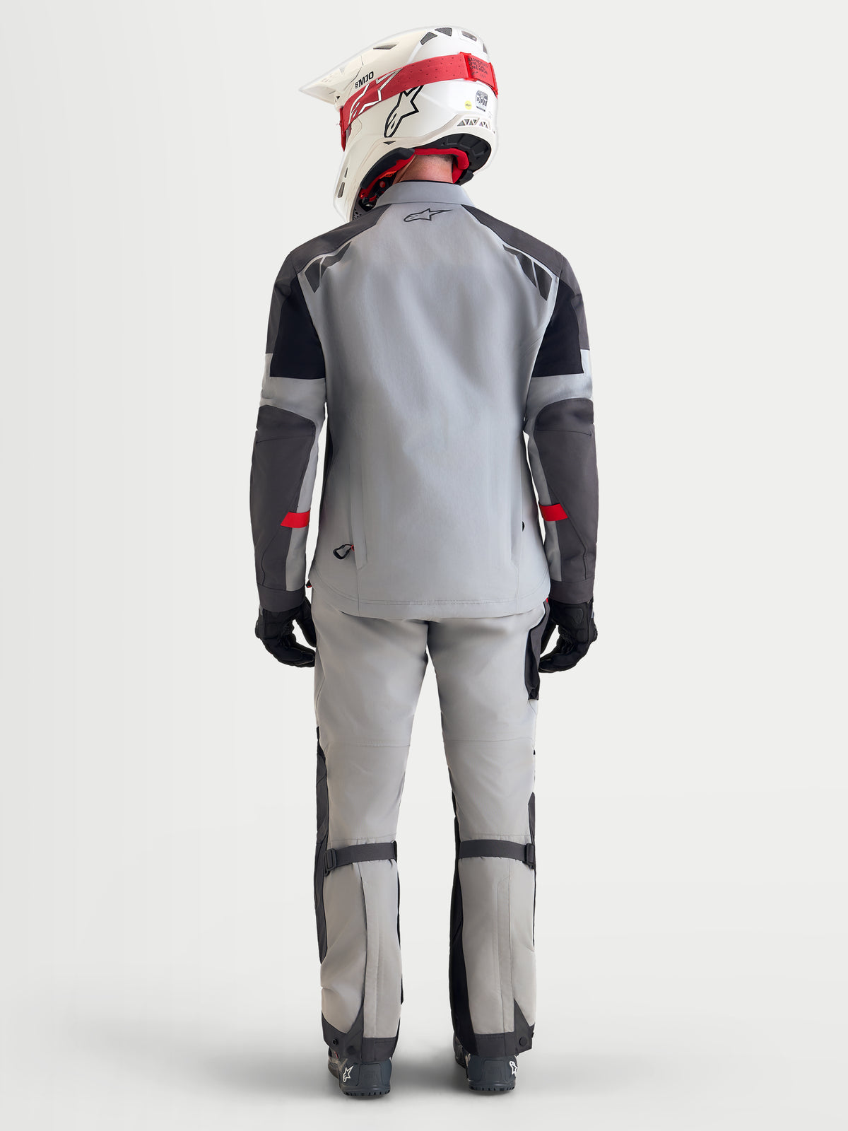 Alpinestars Arenis Gore-Tex® Jacket, men's adventure touring motorcycle jacket in mid gray, deep gray, and black, rear view showing a model wearing the waterproof textile jacket with helmet and riding gear