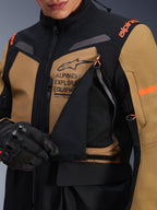 Alpinestars ST-7 2L GORE-TEX Jacke, Adventure-Touring-Motorradjacke, Gobi-Braun und Schwarz, Nahaufnahme des geöffneten Belüftungspanels an der Brust mit atmungsaktivem Mesh-Gewebe, Alpinestars Exploration Equipment Branding und orangefarbene Akzente.