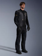 Männliches Model in der Alpinestars ST-7 2L GORE-TEX Jacke in Deep Gray Black und Dark Khaki, kombiniert mit passender schwarzer Adventure-Hose und Handschuhen, mit wasserdichter laminierter Außenschale, Cargotaschen und technischem Branding, ideal für Adventure-Touren.