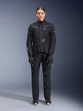 Motorradfahrerin in Alpinestars Damen Stella ST-7 2L GORE-TEX Jacke und Hose, schwarzes Motorrad-Tourenoutfit, wasserdichte und atmungsaktive technische Ausrüstung, mit passenden schwarzen Handschuhen und Stiefeln, Ganzkörper-Schutzausrüstung mit reflektierenden Elementen, modernes technisches Design für Adventure-Riding