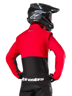 Alpinestars Pro-Dura Jacke, Offroad-Enduro-Jacke, Rot und Schwarz mit weißem Alpinestars-Logo am hinteren Saum, Rückansicht eines Fahrers mit schwarzem Motocross-Helm, Rallye-inspiriertes Design für aggressives Trail-Fahren