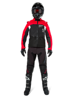 Motocross-Fahrer in kompletter Offroad-Ausrüstung, Alpinestars Pro-Dura Jacke in Schwarz, leuchtendem Rot und Weiß, schwarze Hose mit roten Akzenten, schwarzer Helm mit roter Brille, schwarz-weiße Stiefel, abgestimmtes Outfit für Enduro- und Trail-Fahrten