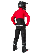 Motocross-Fahrer in der Rückansicht mit der Alpinestars Pro-Dura Jacke in Schwarz, Leuchtend Rot und Weiß, kombiniert mit schwarzer Hose, schwarzem Helm und schwarzen Offroad-Stiefeln, mit rotem oberem und schwarzem unterem Bereich sowie weißem Alpinestars-Branding auf dem Rücken.