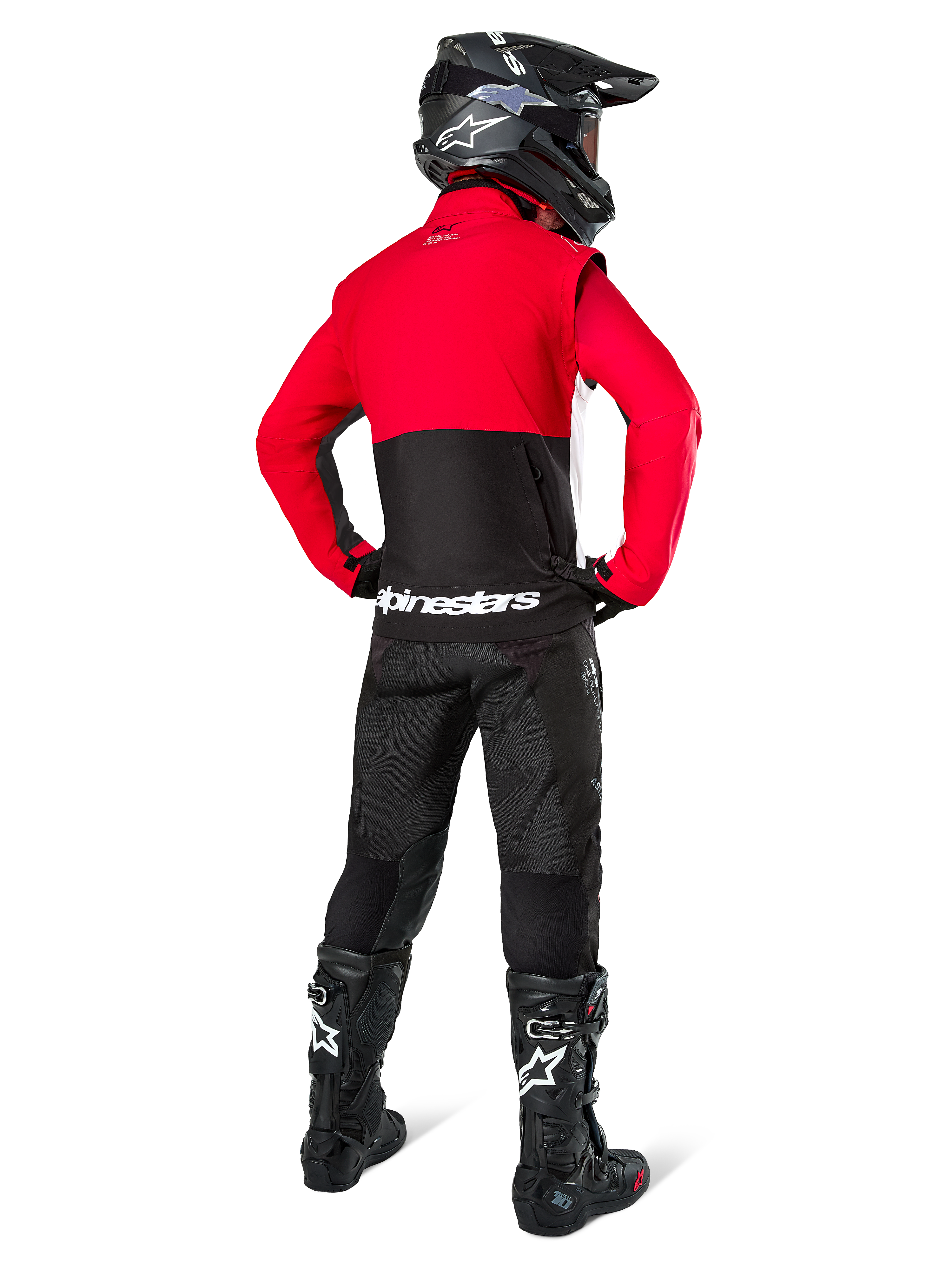 Motocross-Fahrer in der Rückansicht mit der Alpinestars Pro-Dura Jacke in Schwarz, Leuchtend Rot und Weiß, kombiniert mit schwarzer Hose, schwarzem Helm und schwarzen Offroad-Stiefeln, mit rotem oberem und schwarzem unterem Bereich sowie weißem Alpinestars-Branding auf dem Rücken.