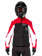 Alpinestars Lite-Dura Softshell-Jacke in Schwarz, Leuchtendrot und Weiß, getragen von einem Motocross-Fahrer mit schwarzem Helm und rot getönter Brille, mit weißen Einsätzen an den Ärmeln, Alpinestars-Branding auf der Brust und einem sportlichen Offroad-Design.