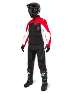 Motocross-Fahrer in der Alpinestars Lite-Dura Softshell-Jacke in Schwarz, leuchtendem Rot und Weiß, schwarzer Rumpf und rot-weiße Ärmel, kombiniert mit schwarzer Hose, schwarzem Helm mit roter Brille und schwarz-weißen Stiefeln, komplette Offroad-Rennausrüstung.