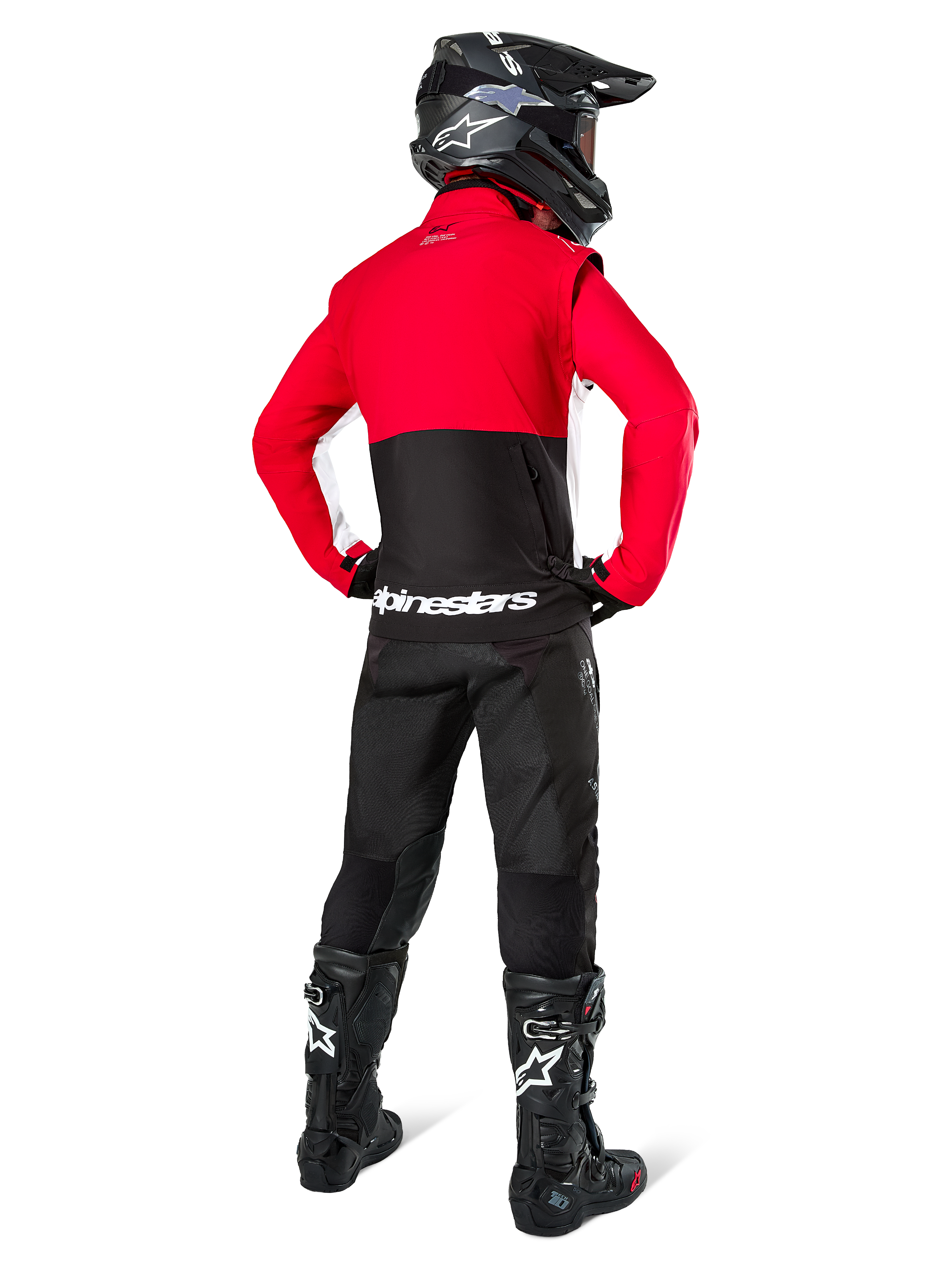 Motocross-Fahrer von hinten in der Alpinestars Lite-Dura Softshell-Jacke, Schwarz, Bright Red und Weiß, mit rotem oberen Panel und schwarzem unteren Bereich mit weißem Branding, kombiniert mit schwarzer Hose, schwarzem Helm und schwarzen Stiefeln, abgestimmtes Enduro-Outfit für Geländefahrten