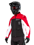 Alpinestars Lite-Dura Softshell-Jacke, Motorradjacke, Schwarz, leuchtendes Rot und Weiß, getragen von einem Fahrer mit schwarzem Motocross-Helm, roter Brille und Handschuhen, mit markantem Branding auf der Brust, konzipiert für Offroad- und Enduro-Fahrten