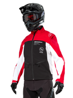Alpinestars Lite-Dura Softshell-Jacke, Motorradjacke, Schwarz, leuchtendes Rot und Weiß, getragen von einem Fahrer mit schwarzem Motocross-Helm, roter Brille und Handschuhen, mit markantem Branding auf der Brust, konzipiert für Offroad- und Enduro-Fahrten