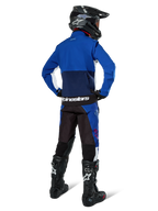 Motocross rider from behind wearing Alpinestars Lite-Dura Softshell Jacket in Navy Bright Blue and White, paired with matching enduro pants, black helmet, and black boots, complete off-road racing gear
