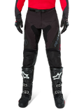 Alpinestars Pro-Dura Hose, Enduro-Hose in Schwarz und Magnet, getragen mit einem roten Langarm-Trikot und schwarzen Motocross-Stiefeln, mit grauem Alpinestars-Branding und strapazierfähiger Ripstop-Konstruktion für Offroad-Fahrten