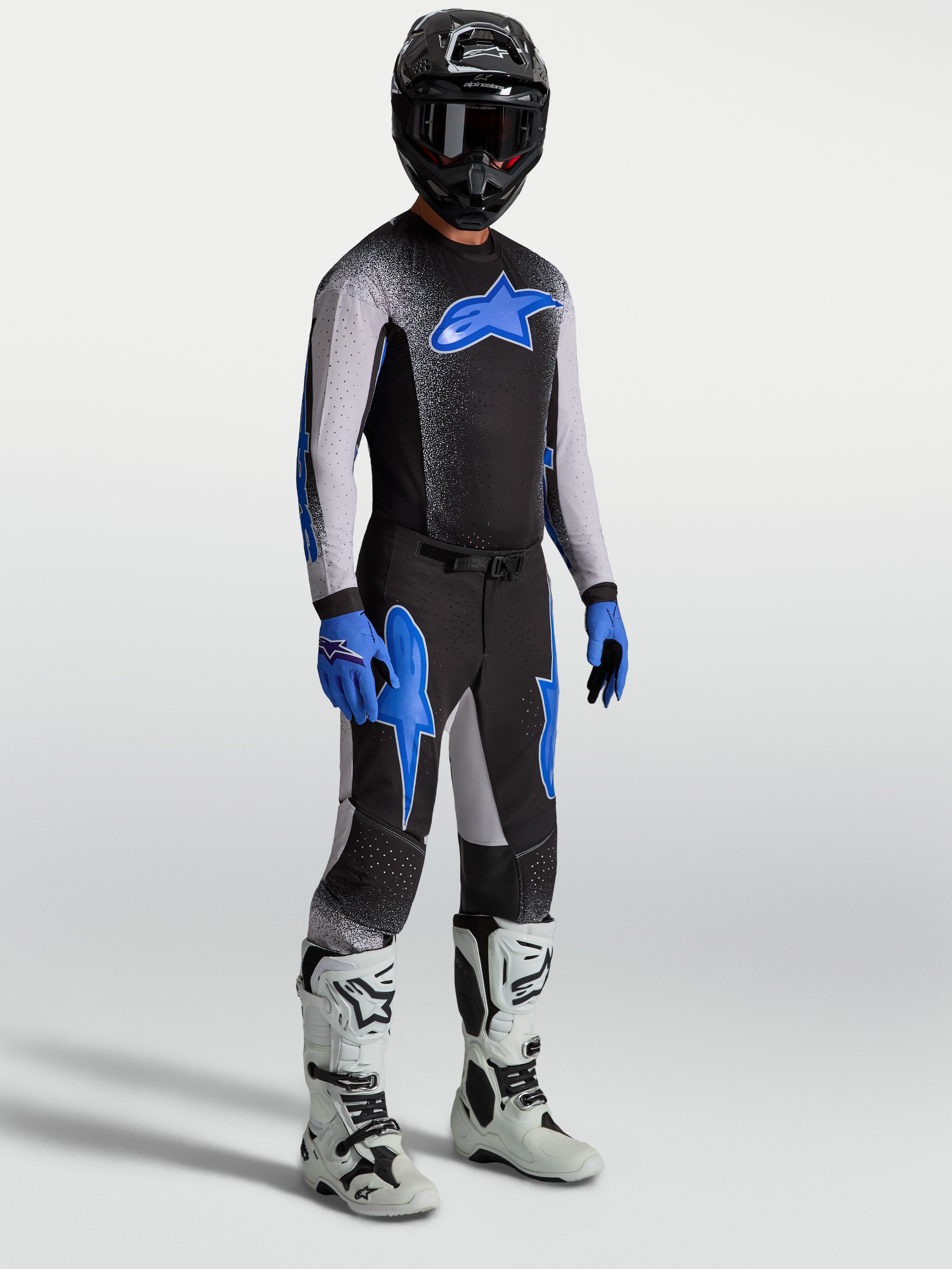 Alpinestars Supertech Hiten AFD Hose, Motocross-Set für Herren in Schwarz und Blau am Model mit Trikot und weißen Stiefeln.