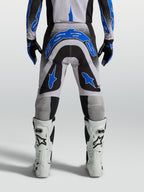 Alpinestars Supertech Hiten AFD Hose, Herren-Motocross-Hose in Schwarz und Blau, athletische Rennpassform, Rückansicht am Model mit weißen Stiefeln.