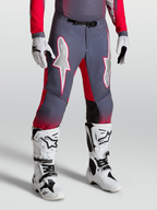 Alpinestars Supertech Hiten AFD Hose, Motocross-Hose in Grau und Rot, mit weißen Sterngrafiken und Magnetschnalle, getragen mit weißen Stiefeln.