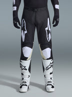 Alpinestars 2026 Racer Air Riway Hose, Motocross-Hose, Schwarz und Weiß, mit markanten weißen Alpinestars-Logos an den Oberschenkeln und Knie-Einsätzen, kombiniert mit weiß-schwarzen Motocross-Stiefeln und schwarzen Handschuhen, athletische Rennpassform für den Offroad-Sport