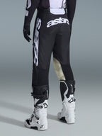 Alpinestars 2026 Racer Air Riway Hose, Motocross-Hose, Schwarz und Weiß, Rückansicht mit großem weißem Astars-Branding auf dem Gesäß und den Beinen, beigefarbene Leder-Einsätze an den Knieinnenseiten, getragen mit weiß-schwarzen Tech 7 Stiefeln, hochwertige Offroad-Rennbekleidung.