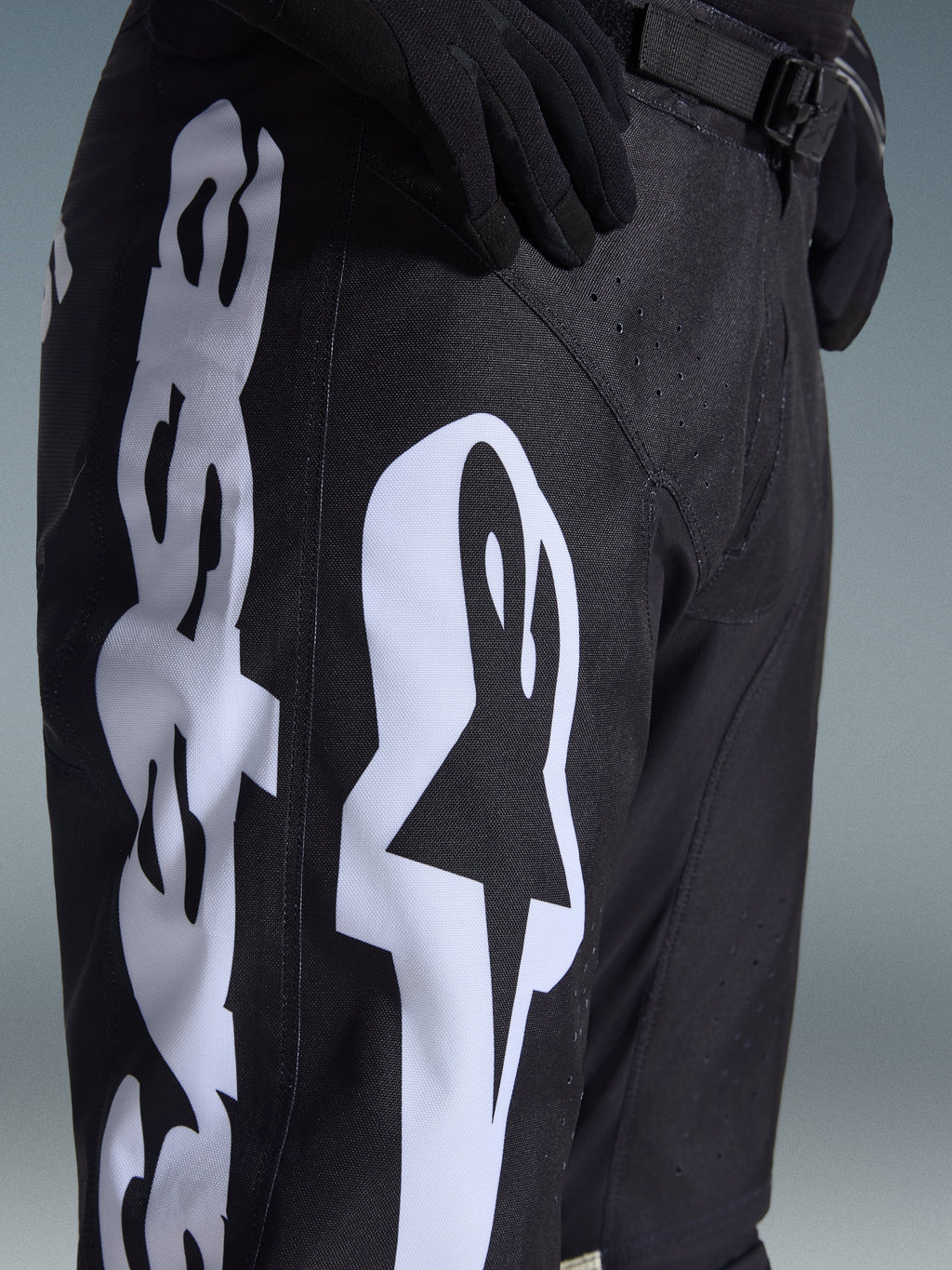 Alpinestars 2026 Racer Air Riway Hose, Motocross-Hose, Schwarz und Weiß, Detailansicht mit großem weißem Alpinestars-Branding, lasergeschnittenen Perforationen für Luftzirkulation und verstellbarer Taillenschnalle, strapazierfähiges Material für Offroad-Einsätze.