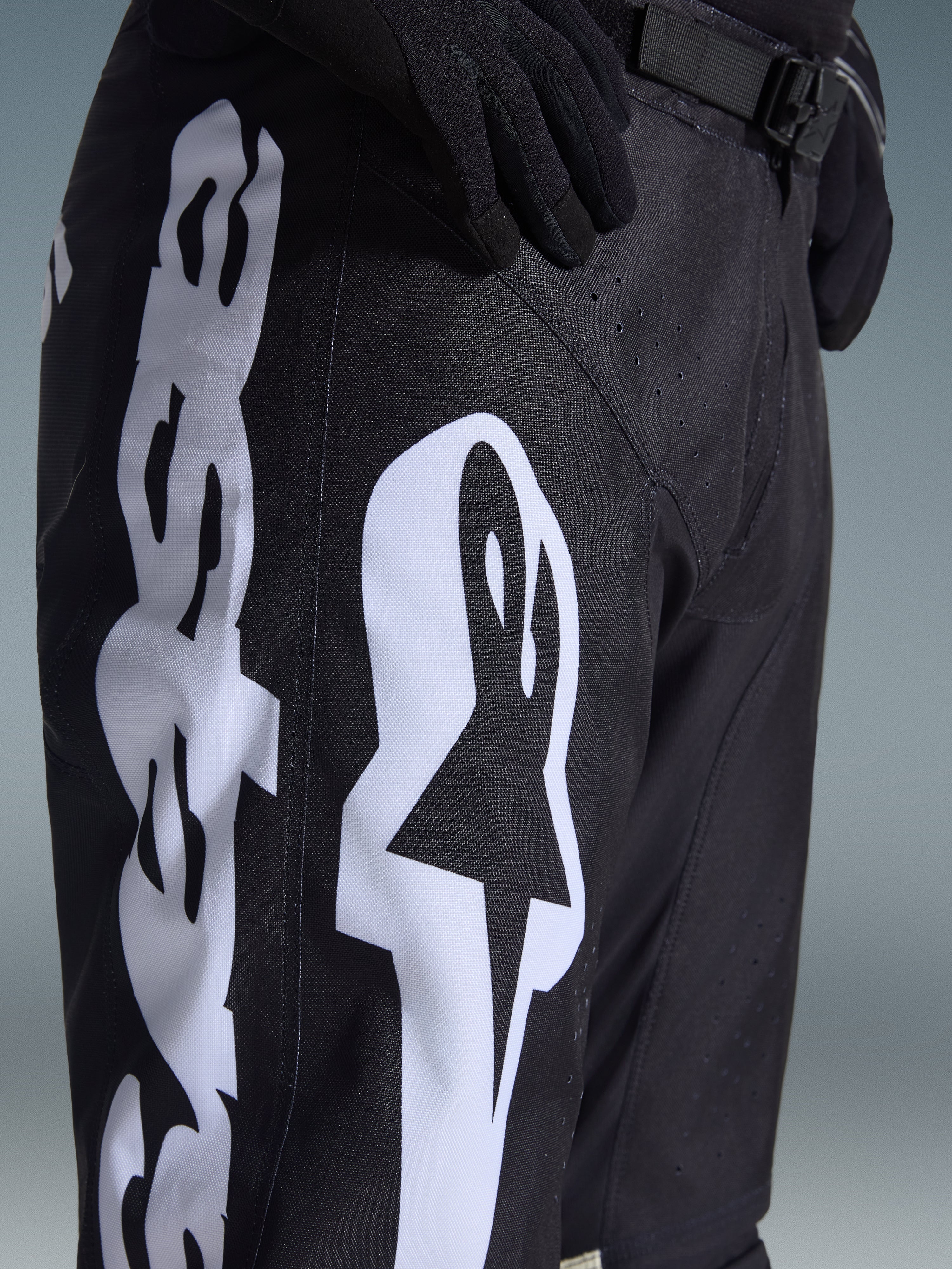 Alpinestars 2026 Racer Air Riway Hose, Motocross-Hose, Schwarz und Weiß, Detailansicht mit großem weißem Alpinestars-Branding, lasergeschnittenen Perforationen für Luftzirkulation und verstellbarer Taillenschnalle, strapazierfähiges Material für Offroad-Einsätze.