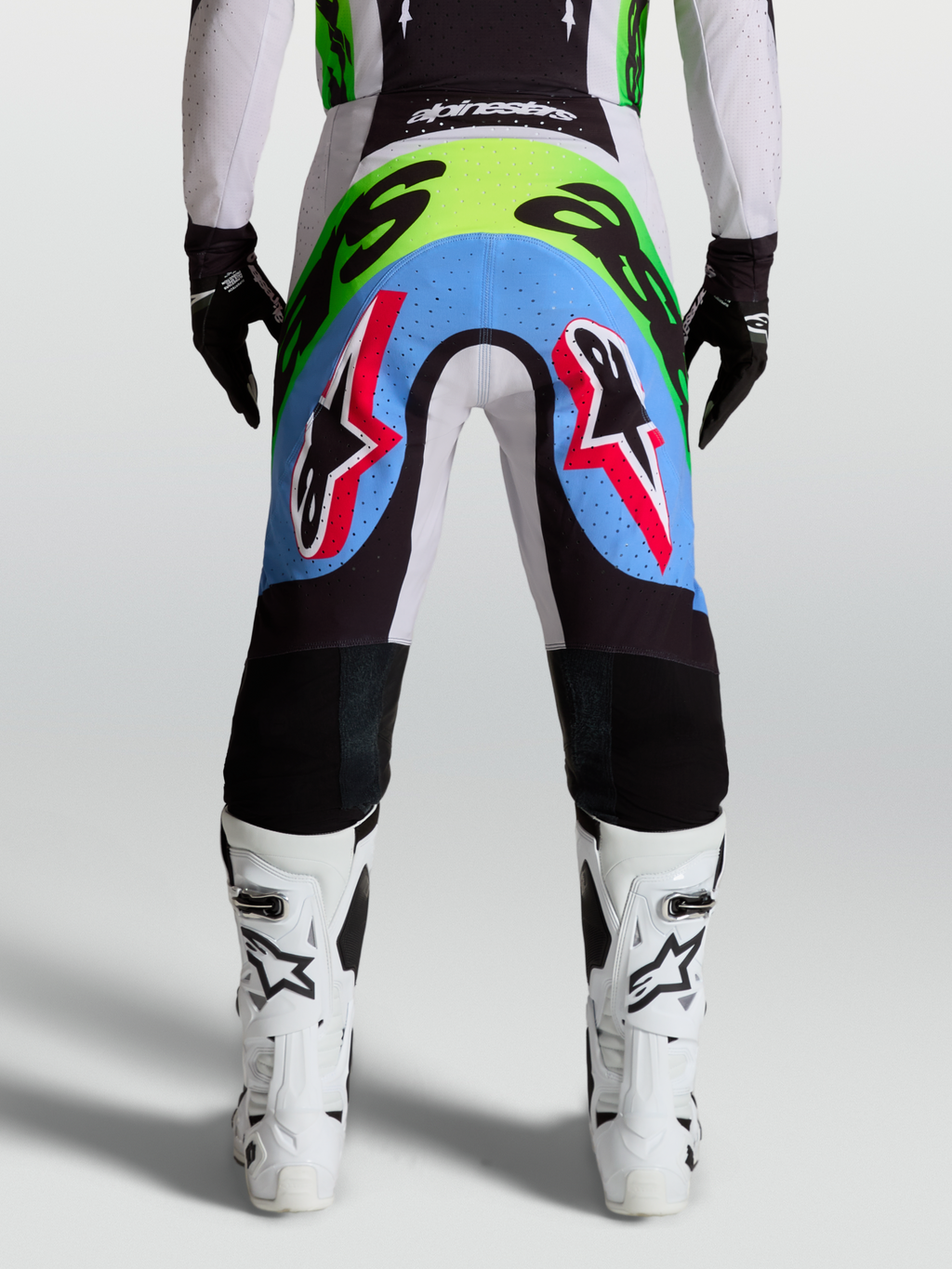 Alpinestars Supertech Dyna Herren-Motocross-Hose, Rückansicht in Helllila und Neongrün mit perforierten Stretcheinsätzen.