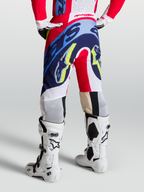 Alpinestars Supertech Dyna Hose, Motocross-Hose in Rot, Weiß und Navy-Blau, athletische Passform am Model, getragen mit weißen Tech 10 Stiefeln, rennerprobte Offroad-Performance-Ausrüstung für MX und SX.