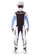 Motocross-Fahrer in Alpinestars 2025 Techstar Melt Hose, Motocross-Hose, Schwarz und Blau, weiß-schwarzes Multi-Panel-Design mit blauen Hüftakzenten, getragen mit passendem weißem Trikot, weißem Helm, weißen Handschuhen und Stiefeln für eine komplette Offroad-Rennausrüstung
