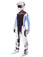 Motocross-Fahrer in Alpinestars 2025 Techstar Melt Hose, weiß-schwarze Motocross-Ausrüstung mit hellblauen Akzenten, passendes Trikot und Handschuhe, weißer Helm und Brille, weiß-schwarze Rennstiefel, professionelle Offroad-Ausrüstung