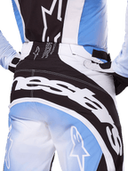 Alpinestars 2025 Techstar Melt Hose, Motocross-Hose, Schwarz, Weiß und Blau, Nahaufnahme der Rückansicht mit markantem weißem Branding auf dem Gesäß, kombiniert mit passendem Techstar Melt Trikot und Handschuhen, professionelle Rennausrüstung für Motocross