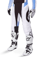 Alpinestars 2025 Techstar Melt Hose, Motocross-Hose, Weiß und Schwarz mit blauen Akzenten, mit lasergeschnittenen Perforationen für Luftzirkulation und Babel-Kniekonstruktion, getragen mit passenden weißen Motocross-Stiefeln und Handschuhen, sportliches Offroad-Rennsport-Design