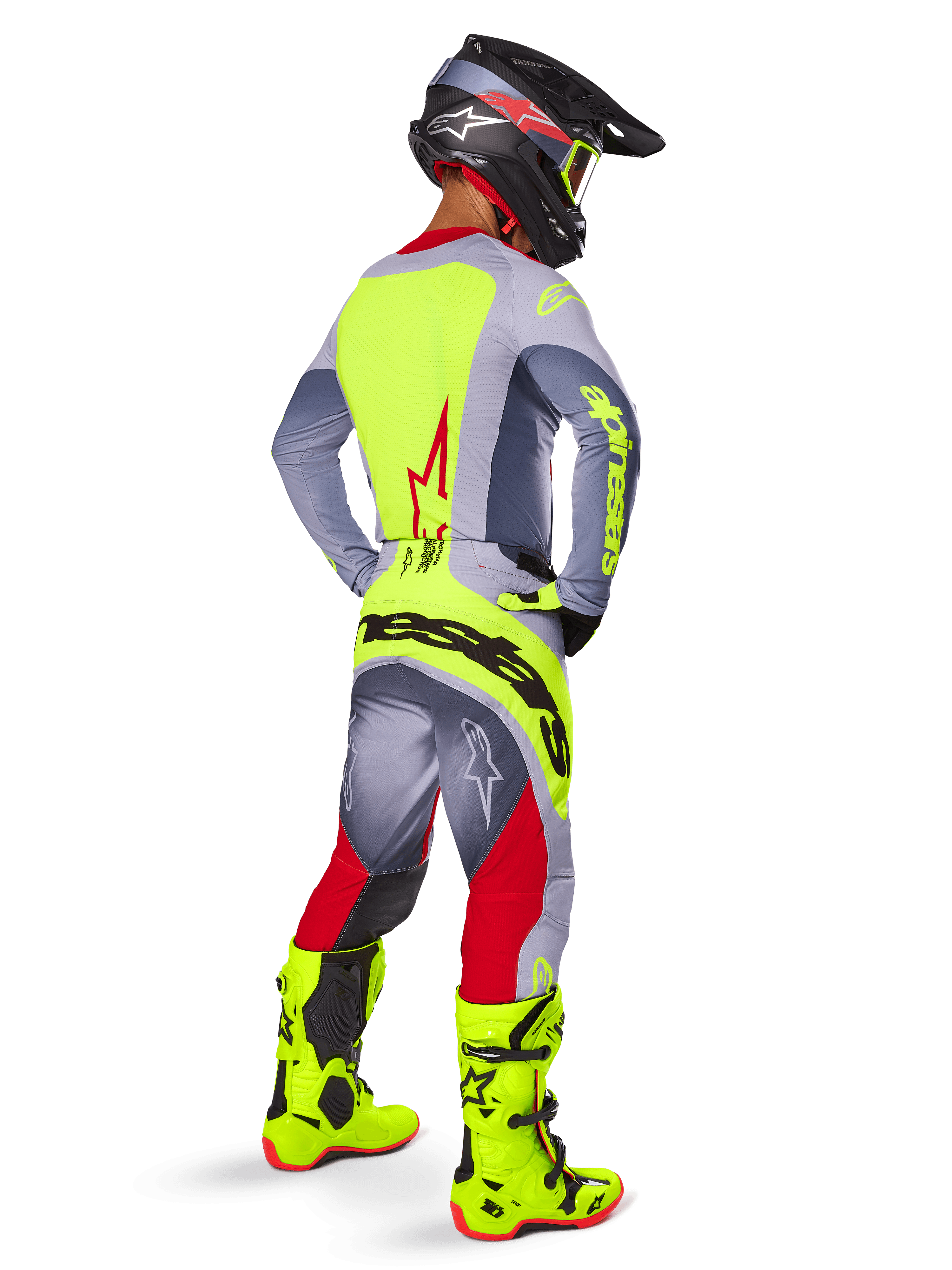 Motocross rider wearing the Alpinestars 2025 Techstar Melt Gear Set, viewed from the back. Gray jersey with a neon yellow back panel and red star logo, gray and red pants with bold neon yellow 'Alpinestars' branding across the seat, bright neon yellow motocross boots, and matching helmet.