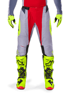 Alpinestars 2025 Techstar Melt Hose, Motocross-Hose, Hellrot-Grau, mit grauem Chassis, roten Mitteleinsätzen und neongelben Seitenakzenten, lasergeschnittene Perforationen zur Belüftung, getragen mit neongelben Handschuhen und Stiefeln, Hochleistungsausrüstung für Offroad-Rennsport