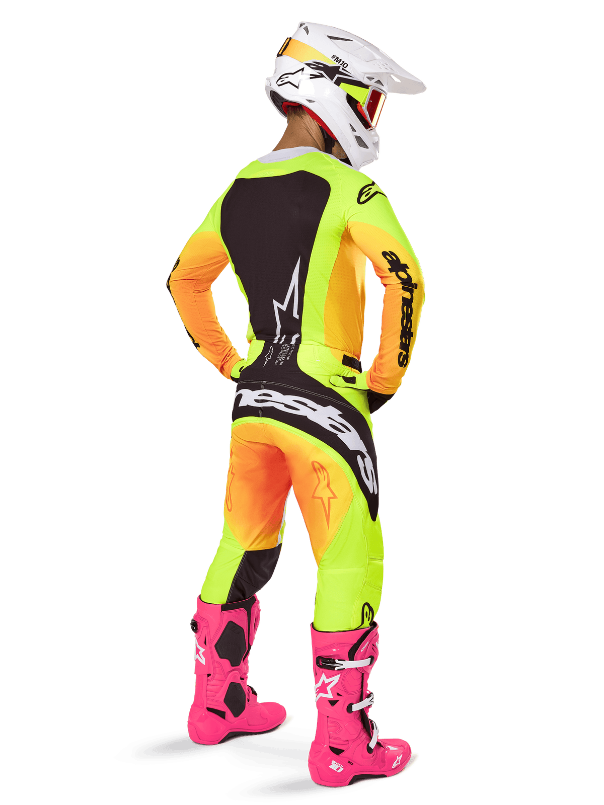 Motocross rider from behind wearing the Alpinestars 2025 Techstar Melt Gear Set, yellow and orange gradient jersey and pants with black panels, white helmet with red goggles, bright pink boots, coordinated racing outfit for off-road performance