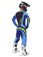 Alpinestars 2025 Techstar Melt Hose, Motocross-Ausrüstung, Gelb Fluo Blau, Rückansicht eines Fahrers in passendem blauem Trikot mit großem gelbem Branding, weißen und schwarzen Stiefeln und schwarzem Helm, koordiniertes Rennoutfit für Offroad-Performance